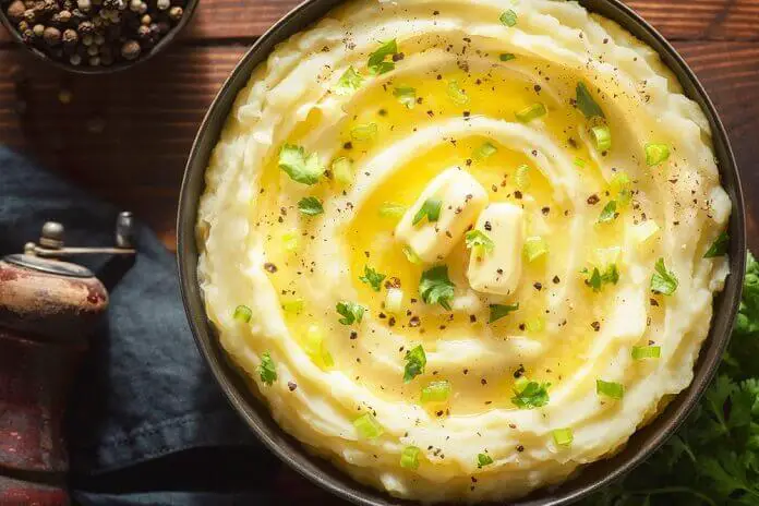 Delicious creamy mashed potatoes with butter, fresh herbs and freshly cracked black pepper