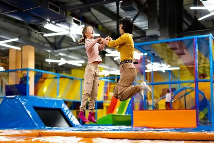 Pretty girl and her daughter kid jumping on colorful trampoline park