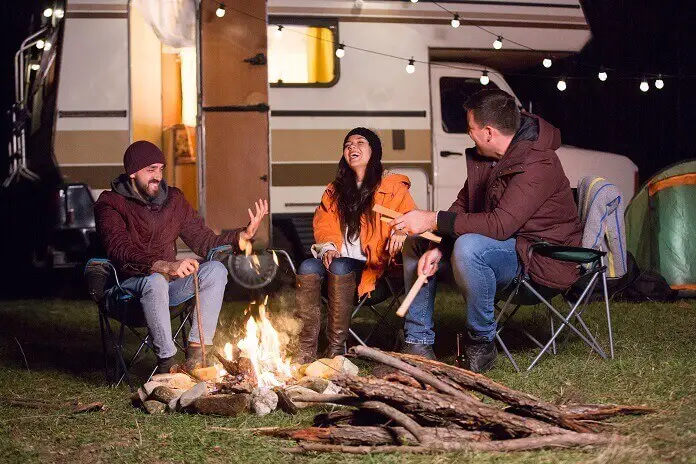 Girl laughing hard after her friends told joke around camp fire with their Rv