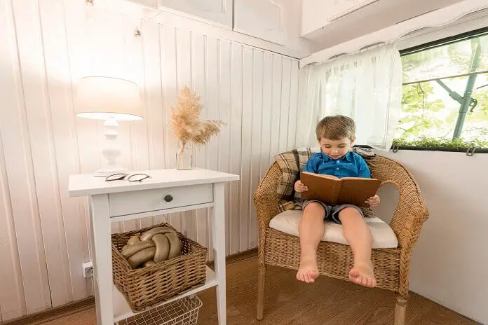 little boy reading book while sitting armchair in Rv