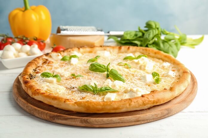 Delicious pizza with cheese and basil on table
